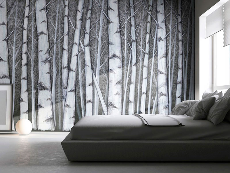 Wallpaper with birch forest painted by hand on a green material background which adorns a bedroom